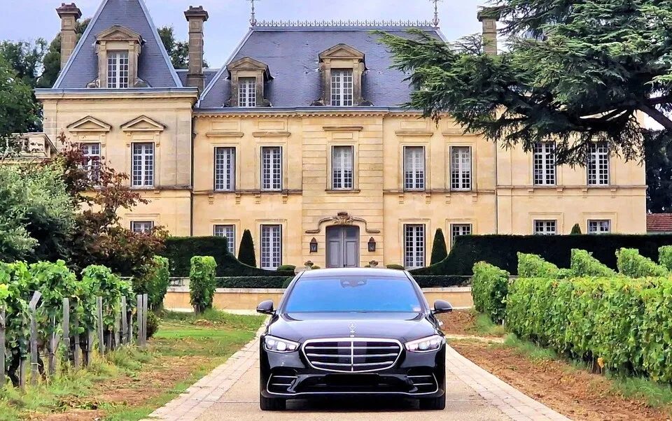 Mercedes Classe S noire garée face à un château du vignoble bordelais.